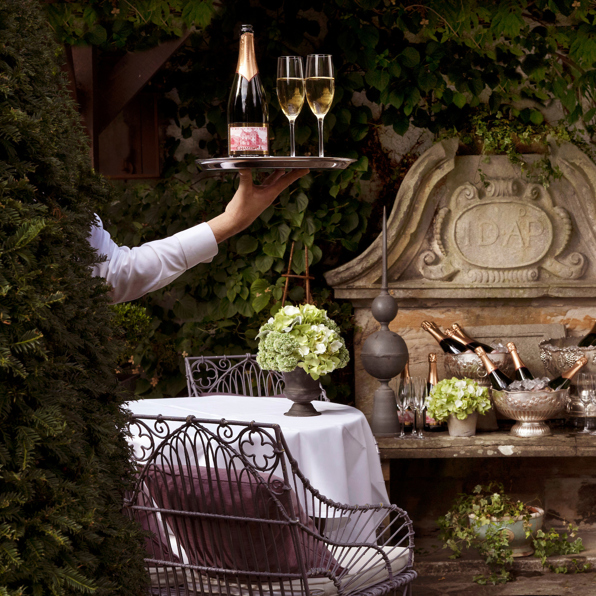 Waiter holds tray with champagne in the Prestonfield House' private dining space Garden Room's terrace